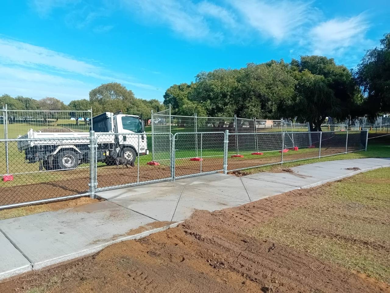Galvanised chainmesh fence and double gate along a new concrete footpath at a park