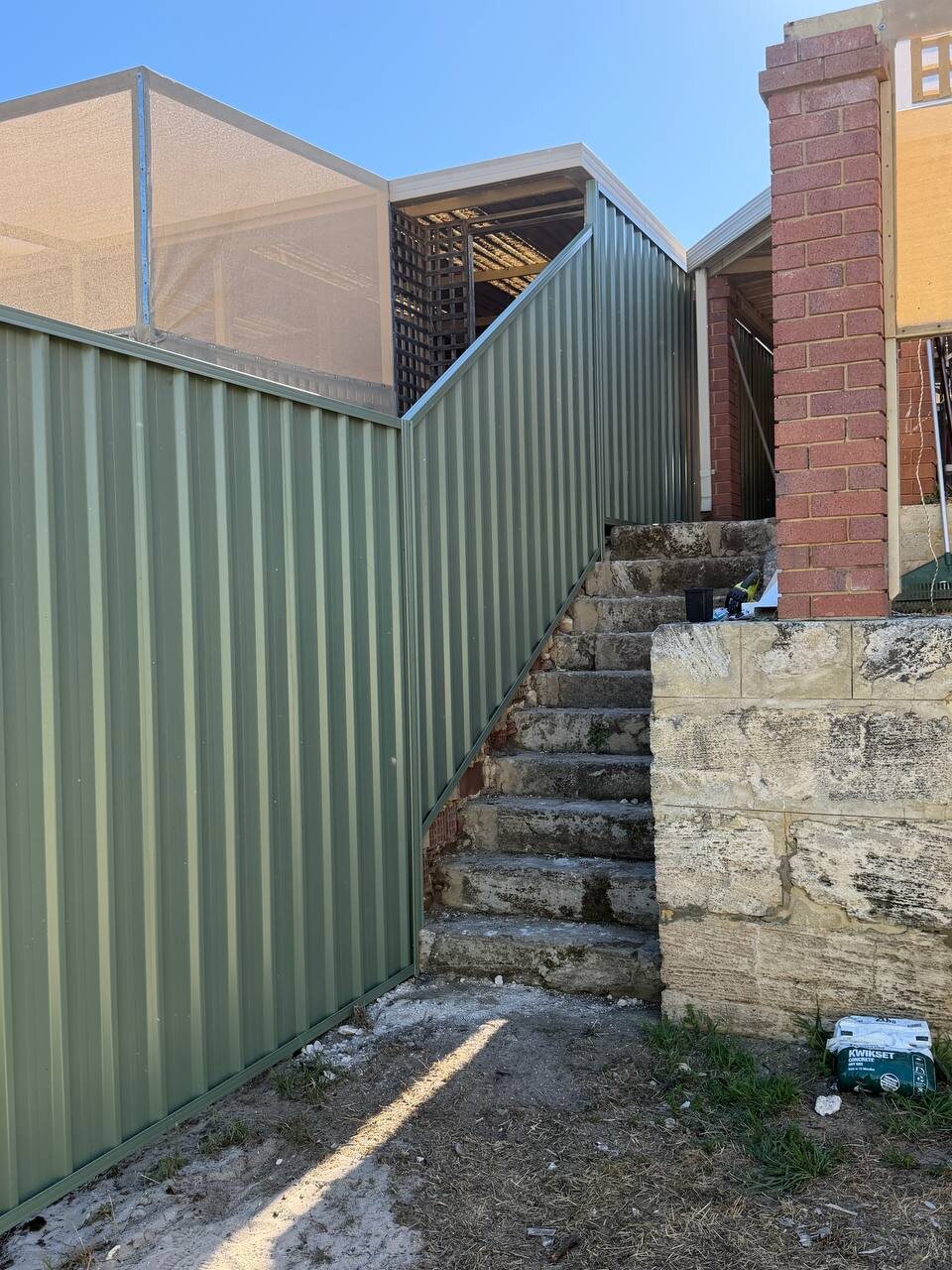 Green Colorbond fence beside steps