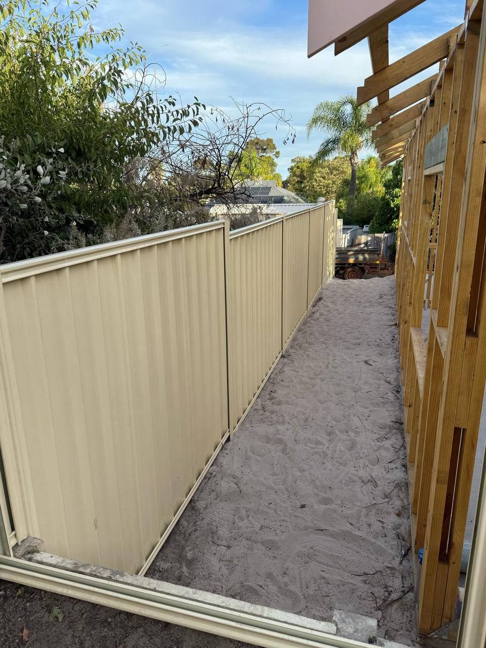 Cream Colorbond side fence beside a new timber-frame build